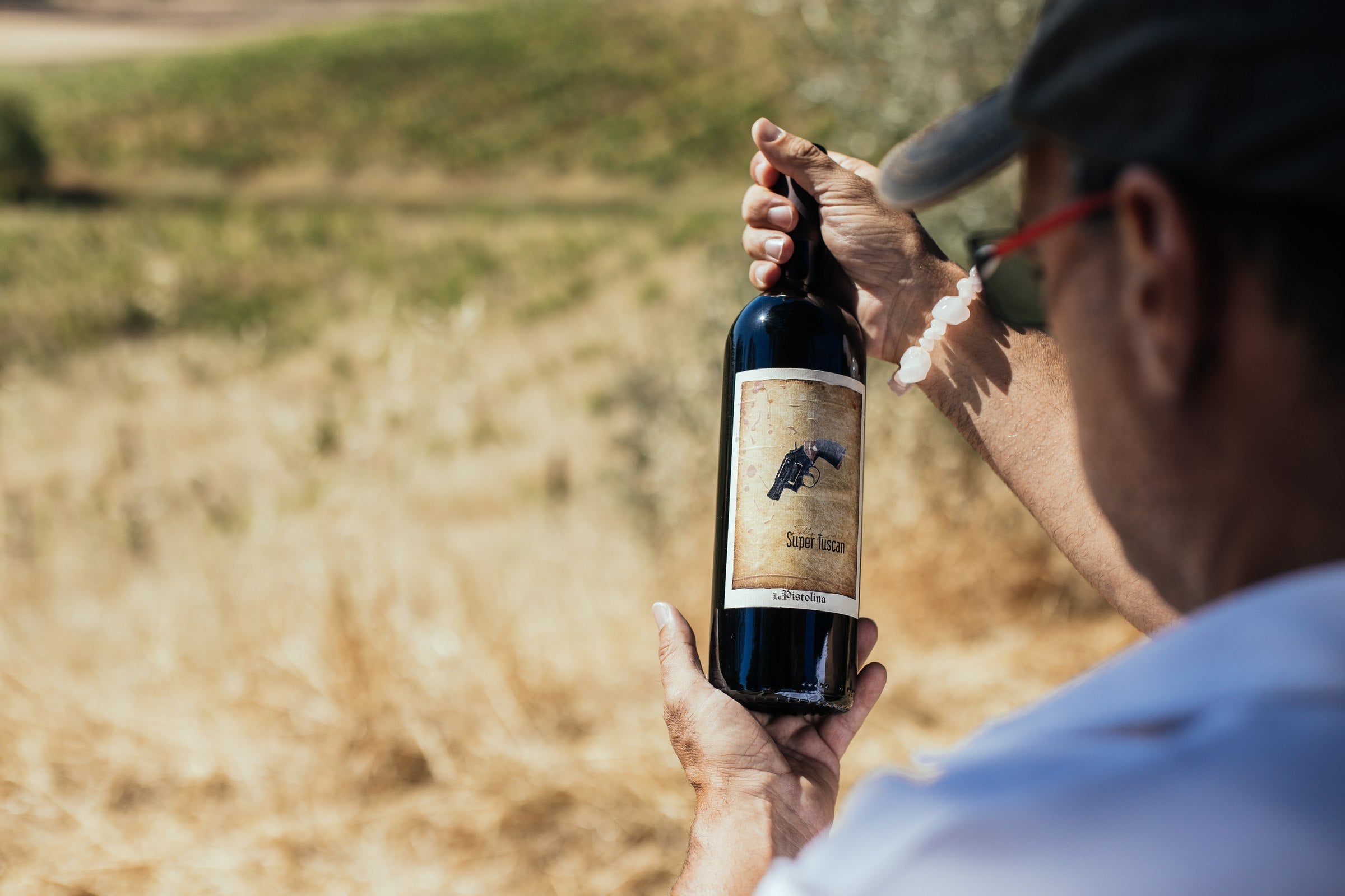 Michael Giordano holding a bottle of La Pistolina in a Tuscan vineyard